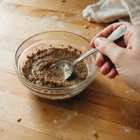 Water being stirred into the ground flaxseed with a spoon, still loose and runny