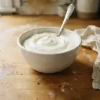 A small bowl of thick plain Greek yogurt with a spoon